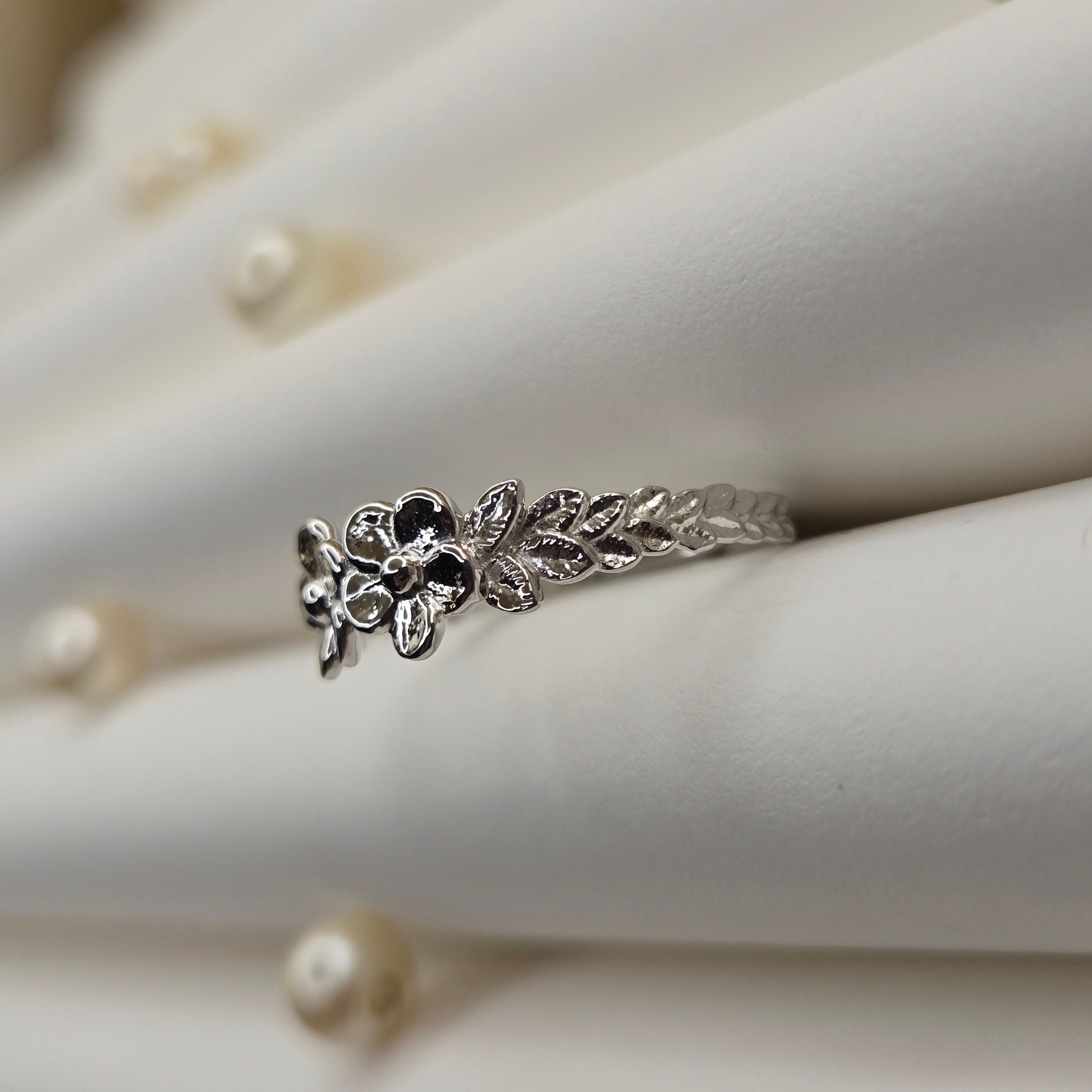 Minimalistic rhodium tone flower band ring with smooth petal detailing, perfect for stacking or wearing as a subtle statement piece.