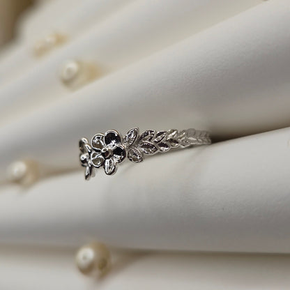 Minimalistic rhodium tone flower band ring with smooth petal detailing, perfect for stacking or wearing as a subtle statement piece.