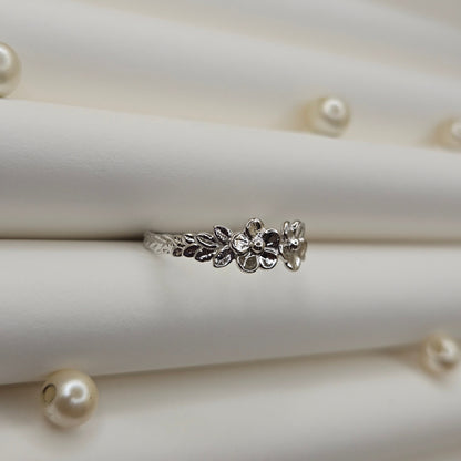 Minimalistic rhodium tone flower band ring with smooth petal detailing, perfect for stacking or wearing as a subtle statement piece.